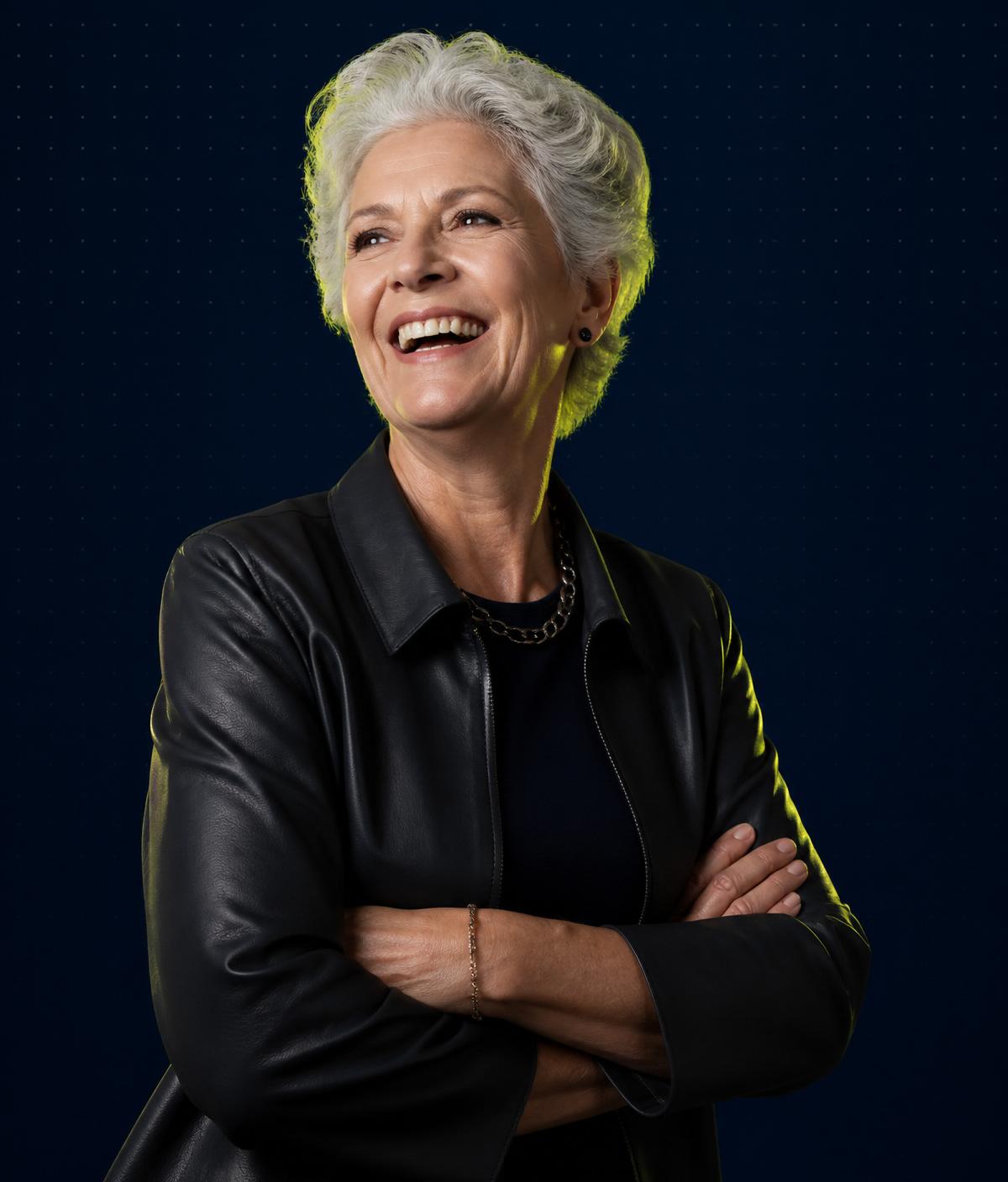 Confident woman in her sixties laughing, lit against a deep navy background